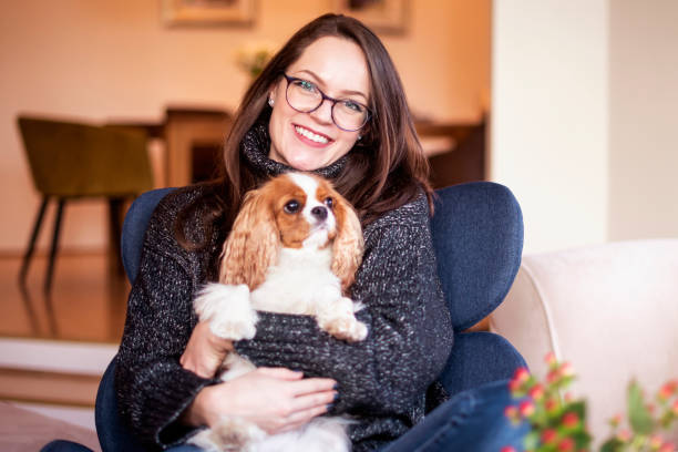 Shot of young woman with her cute puppy relaxing in the armchair at home.