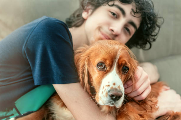 Child boy of Hispanic ethnicity hugging his cocker spaniel pet dog. The image has a light leak applied