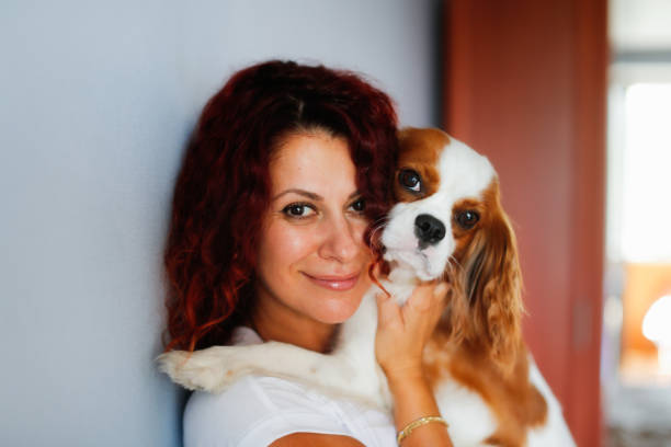 Cute European woman with a Cavalier King Charles Spaniel dog. Woman holding and hugging a small dog