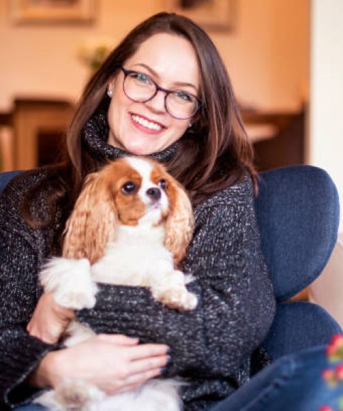 Shot of young woman with her cute puppy relaxing in the armchair at home.